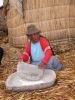 Uros - A woman grinding cereal on Uros floating island